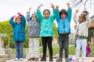 Picture of group of kids laughing with their hands in the air.